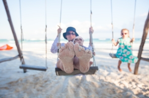 young mother and her cute daughter swinging on a swing at the beach